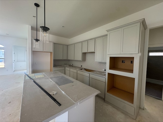 kitchen featuring decorative backsplash, hanging light fixtures, gray cabinets, and a center island