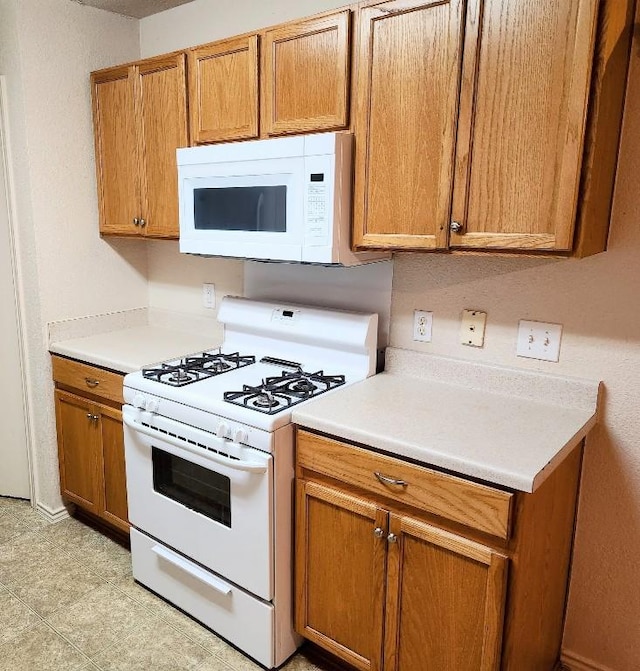 kitchen with brown cabinets, white appliances, and light countertops