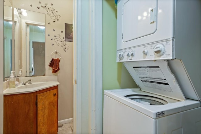 clothes washing area featuring light tile patterned floors, stacked washer and dryer, a sink, and laundry area