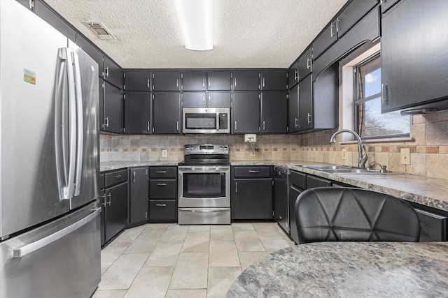 kitchen featuring light tile patterned floors, stainless steel appliances, tasteful backsplash, visible vents, and a sink