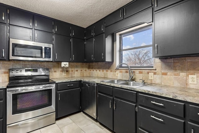 kitchen with light tile patterned floors, a sink, light countertops, appliances with stainless steel finishes, and decorative backsplash