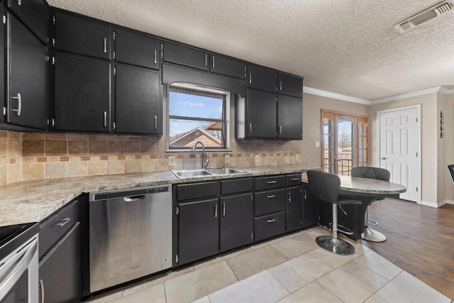 kitchen with appliances with stainless steel finishes, visible vents, a sink, and dark cabinets