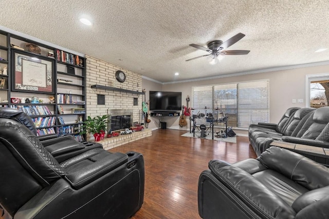 living area featuring a ceiling fan, ornamental molding, wood finished floors, a textured ceiling, and a brick fireplace