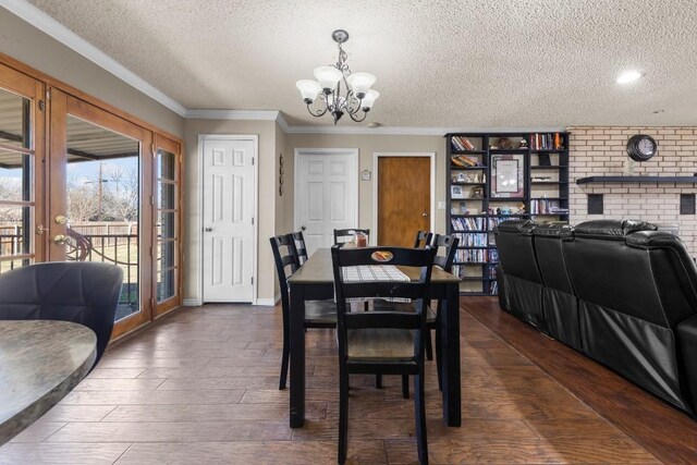 dining area with baseboards, dark wood-type flooring, an inviting chandelier, crown molding, and a textured ceiling