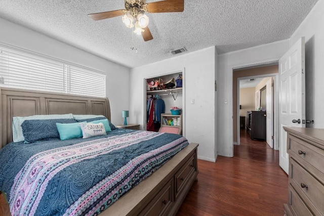 bedroom with ceiling fan, a textured ceiling, dark wood-type flooring, visible vents, and a closet