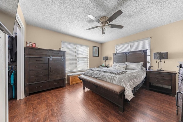 bedroom featuring dark wood-style floors, multiple windows, a textured ceiling, and a ceiling fan