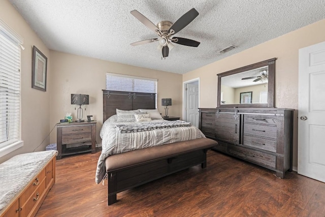 bedroom featuring ceiling fan, a textured ceiling, dark wood finished floors, and visible vents