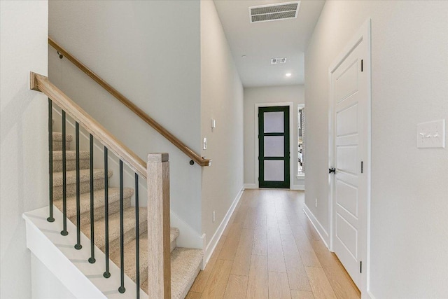 corridor with wood finished floors, stairway, recessed lighting, and baseboards