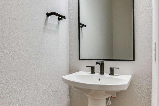 bathroom featuring a textured wall and a sink