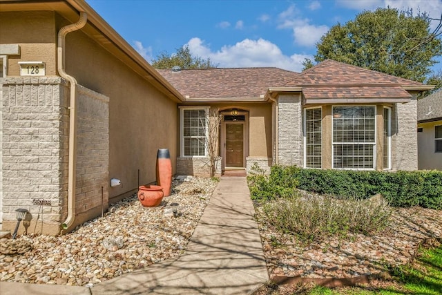 entrance to property with roof with shingles and stucco siding