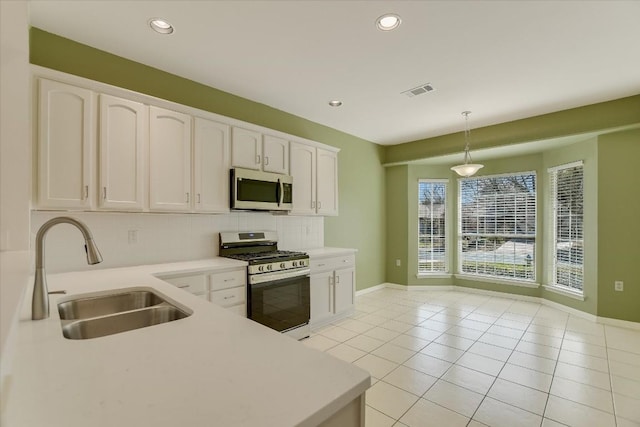 kitchen featuring appliances with stainless steel finishes, light countertops, a sink, and white cabinetry