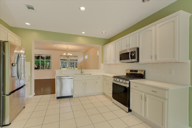 kitchen featuring stainless steel appliances, light countertops, white cabinetry, pendant lighting, and a sink