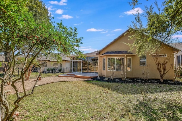 back of property with glass enclosure, fence, stucco siding, and a yard