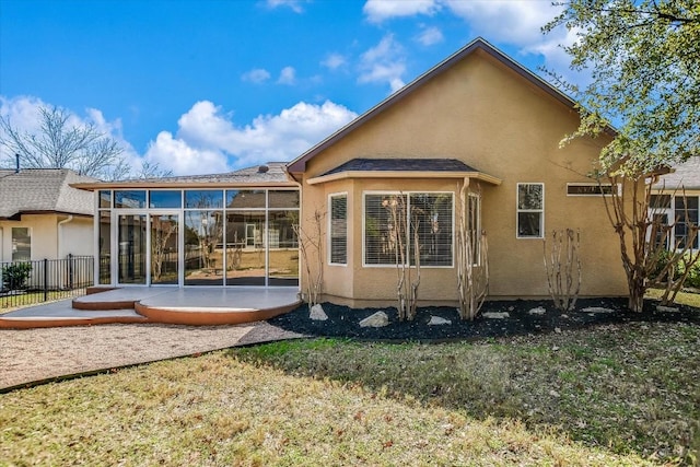 rear view of property featuring a patio area, a yard, fence, and stucco siding