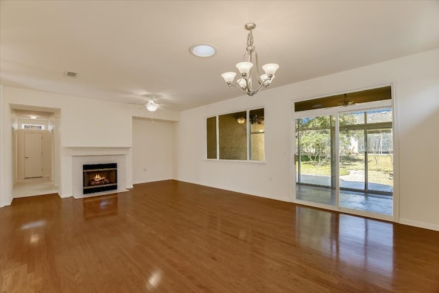 unfurnished living room with baseboards, visible vents, a fireplace with flush hearth, dark wood-style flooring, and ceiling fan with notable chandelier