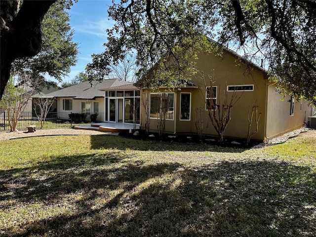 back of house featuring fence, a sunroom, a lawn, stucco siding, and a patio area