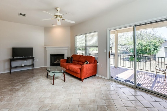 living room with a ceiling fan, a fireplace, and baseboards