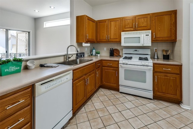 kitchen with light countertops, white appliances, brown cabinetry, and a sink