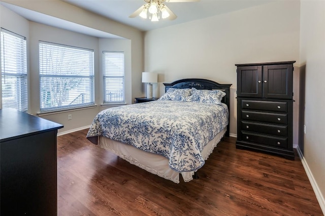 bedroom with dark wood finished floors, a ceiling fan, and baseboards