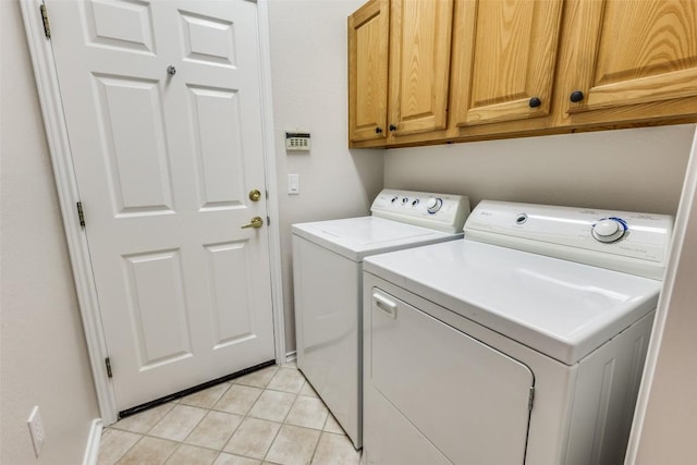 clothes washing area with light tile patterned floors, cabinet space, and washer and dryer