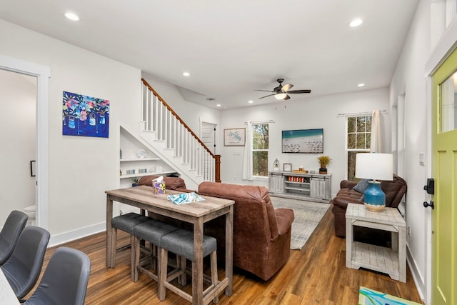 living room featuring stairs, recessed lighting, baseboards, and wood finished floors