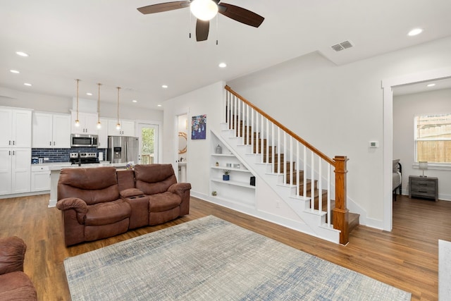 living area with stairway, visible vents, light wood finished floors, and recessed lighting