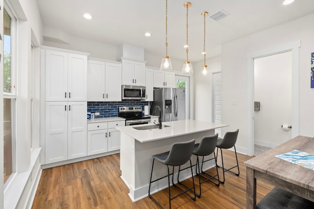578 Firefly Dr, Canyon Lake, TX 78133 - kitchen featuring appliances with stainless steel finishes, a kitchen island with sink, backsplash, white cabinetry, and recessed lighting