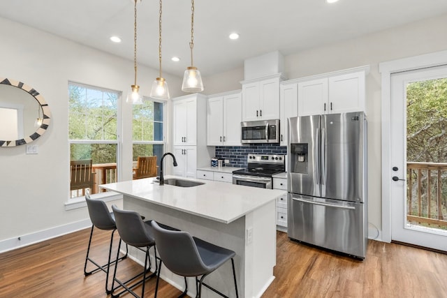 kitchen with a sink, white cabinets, light countertops, appliances with stainless steel finishes, and an island with sink