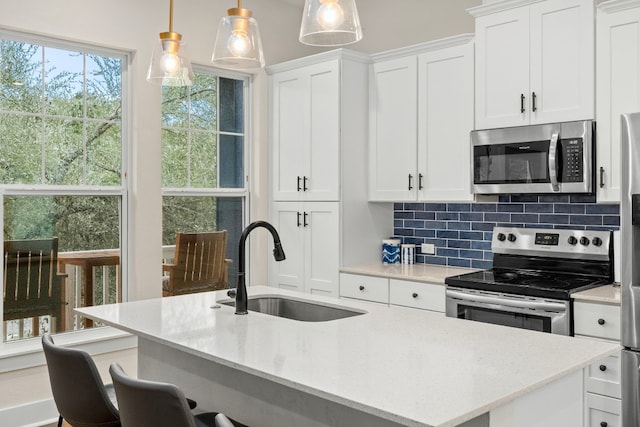 578 Firefly Dr, Canyon Lake, TX 78133 - kitchen featuring appliances with stainless steel finishes, decorative backsplash, white cabinets, a breakfast bar area, and an island with sink