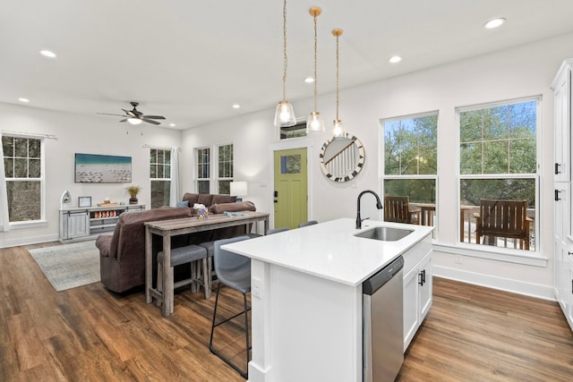 kitchen featuring white cabinets, open floor plan, a kitchen island with sink, stainless steel dishwasher, and a sink