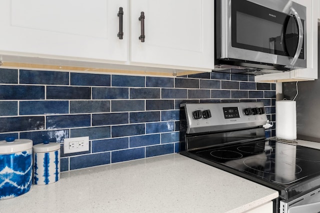 kitchen featuring light countertops, appliances with stainless steel finishes, decorative backsplash, and white cabinets