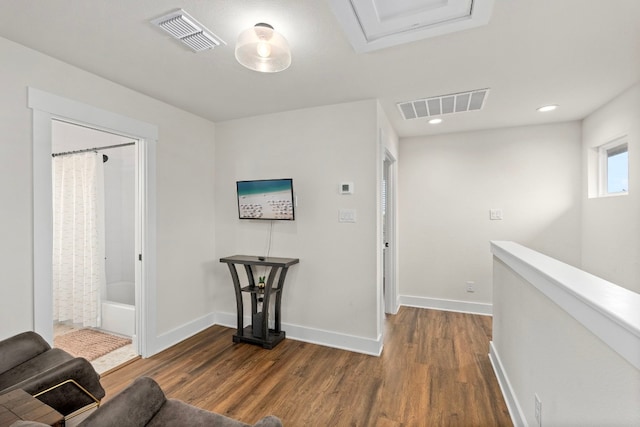 hallway with dark wood-style flooring, visible vents, and baseboards