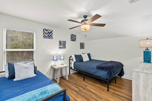 bedroom with wood finished floors, a ceiling fan, visible vents, vaulted ceiling, and baseboards