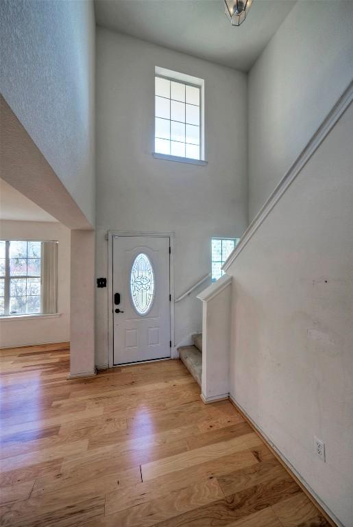 entryway with a high ceiling, stairway, and light wood-type flooring