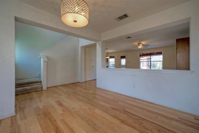 unfurnished living room featuring light wood finished floors, ceiling fan, stairs, and visible vents