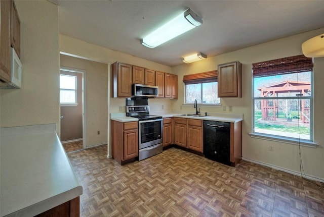 kitchen featuring light countertops, appliances with stainless steel finishes, a sink, and a healthy amount of sunlight