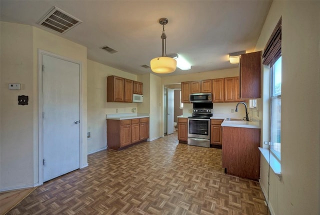 kitchen featuring visible vents, hanging light fixtures, stainless steel appliances, light countertops, and a sink