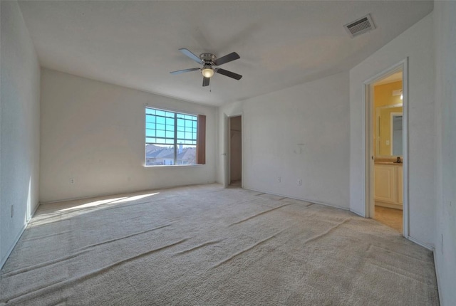 unfurnished bedroom with ensuite bathroom, a ceiling fan, visible vents, and light colored carpet