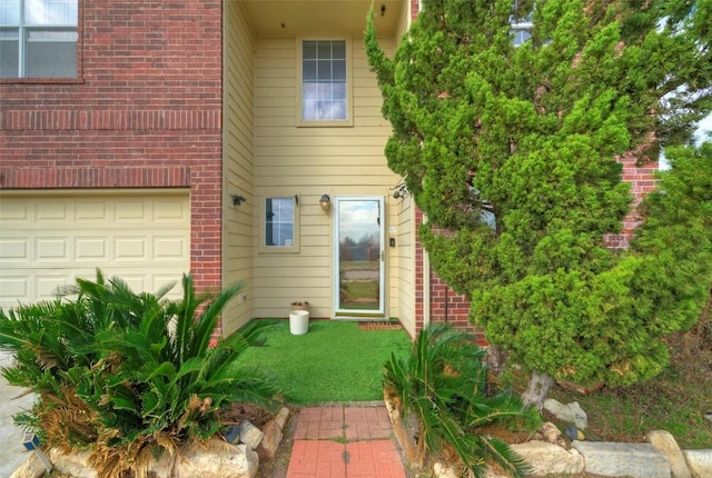 entrance to property with an attached garage and brick siding