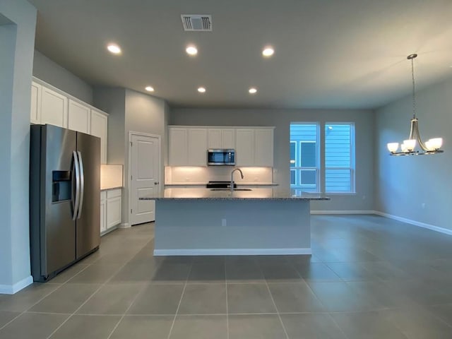 kitchen with stainless steel appliances, visible vents, an island with sink, and white cabinetry