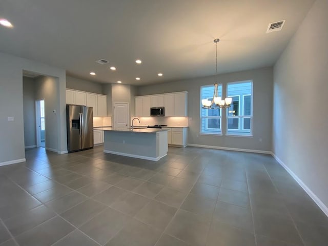 kitchen featuring a kitchen island with sink, visible vents, white cabinetry, appliances with stainless steel finishes, and an inviting chandelier