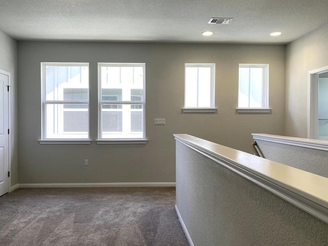 corridor featuring carpet floors, visible vents, plenty of natural light, and baseboards