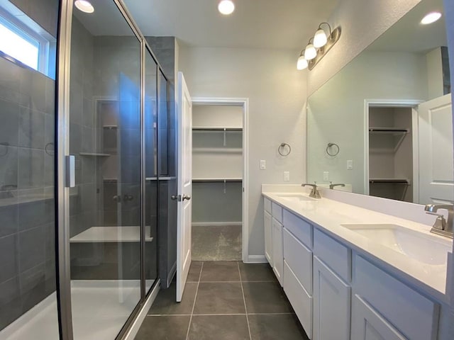 bathroom featuring double vanity, a shower stall, a spacious closet, and a sink