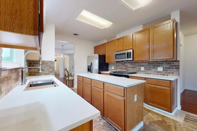 kitchen with visible vents, a sink, stainless steel appliances, light countertops, and backsplash