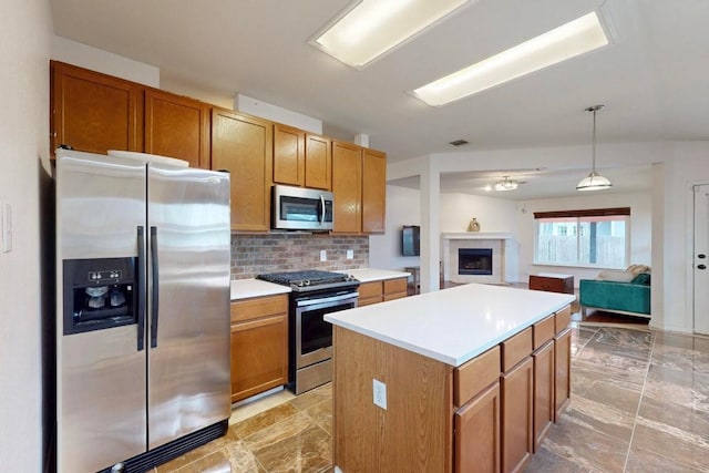 kitchen with appliances with stainless steel finishes, open floor plan, light countertops, and decorative light fixtures