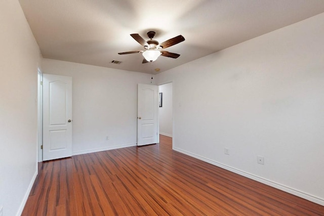 spare room with ceiling fan, dark wood-type flooring, visible vents, and baseboards