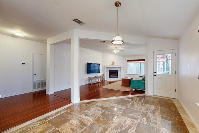 foyer entrance with a fireplace, wood finished floors, and visible vents