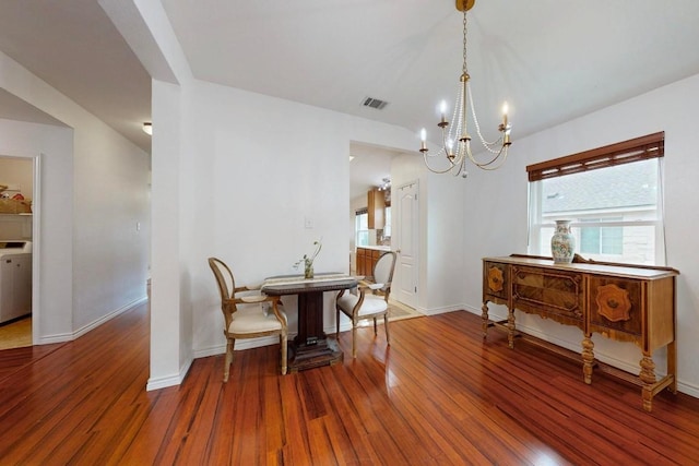 dining space with a notable chandelier, visible vents, baseboards, and hardwood / wood-style floors