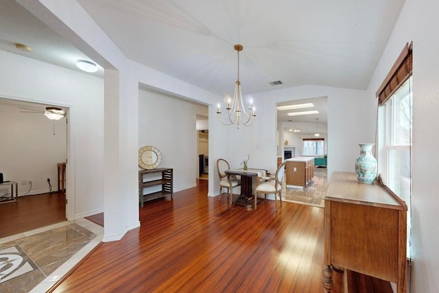 dining area with visible vents, baseboards, wood finished floors, and vaulted ceiling