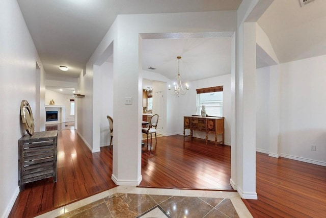 corridor featuring a notable chandelier, baseboards, and wood finished floors